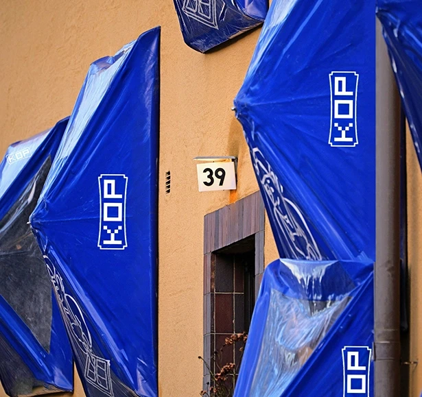 Building facade with blue packages covering windows, numbered 39 on the wall.