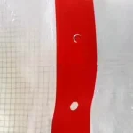 Close-up of the Clear String Reinforced Poly Tarps – 7 oz FR SCAFFOLD SHEETING, showcasing a translucent plastic sheet with a red vertical stripe featuring small round holes at regular intervals and a faint grid pattern.