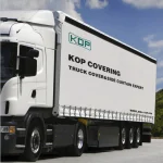 A white truck featuring a side curtain that reads "KOP Covering Truck Tarp & Side Curtain Expert" along with the website www.asia-kop.com, is parked on a concrete surface with trees in the background.