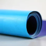 Close-up of a rolled-up blue Heavy Duty Tarpaulin roll with a textured surface, placed on a light-colored background.