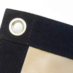 Close-up of a black fabric edge with a metal grommet and overlapping beige material on the Lumber Tarp for Flatbed Truck and Trailer.